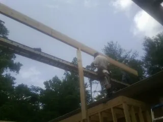 Carpenter setting a ridge beam over a new addition frame — Ice Dam Removal by Roofing Brothers in Bogart