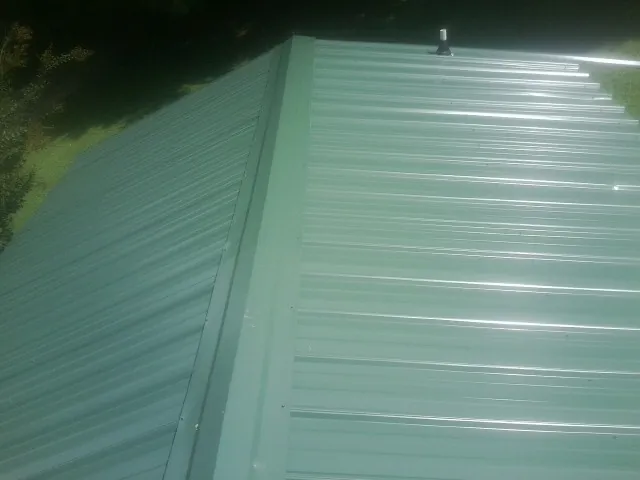 New green metal panels meeting at the ridge of a roof — Flat Roof Repair work by our crew in Bogart
