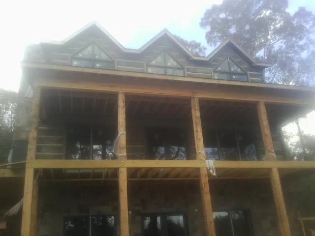 Dormers and porch framing on a large log home under construction — Roof Coating work by our crew in Bogart