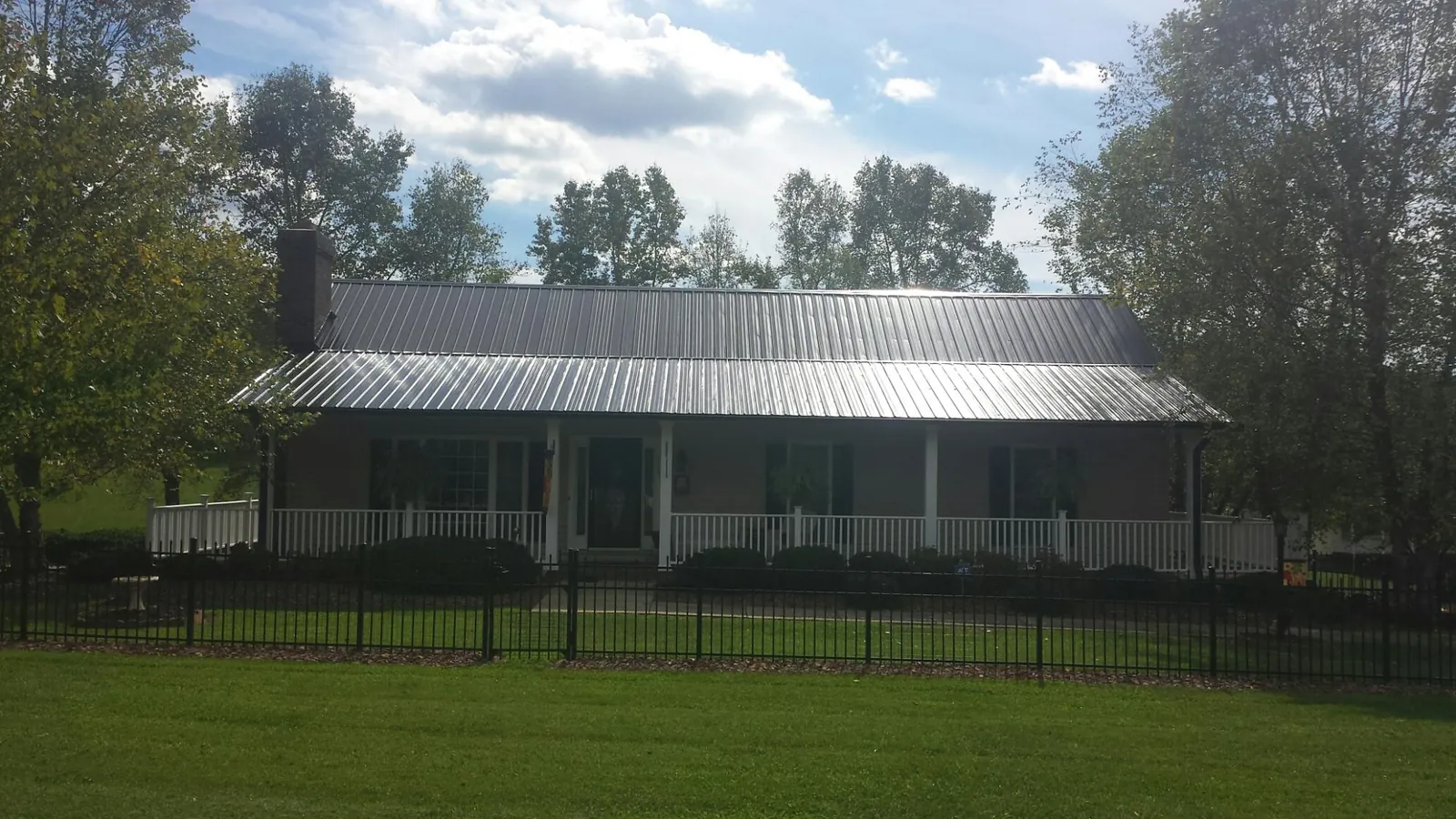 Gray metal roof on a brick ranch with a full width front porch — Gutter Guard Installation work by our crew in Bogart