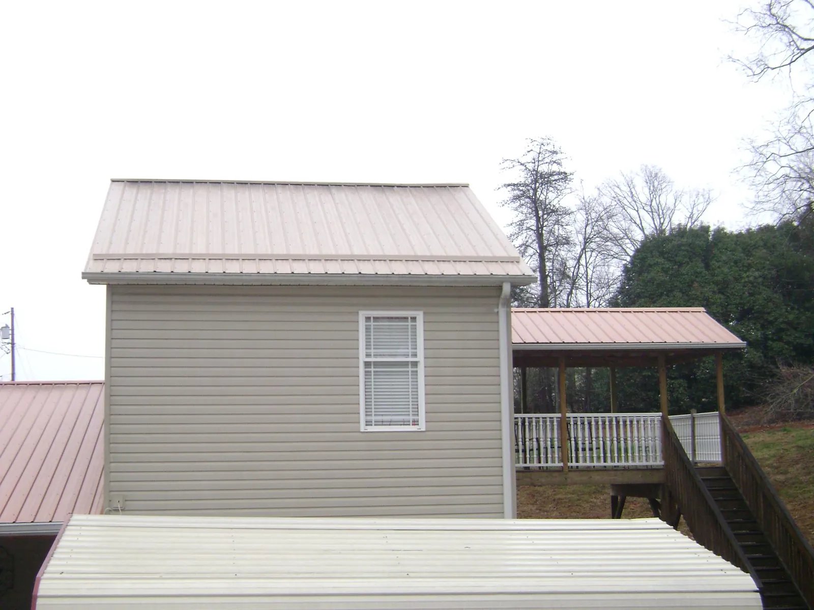 Tan metal roofs on a two story addition and attached porch, from a Roof Replacement job in Bogart