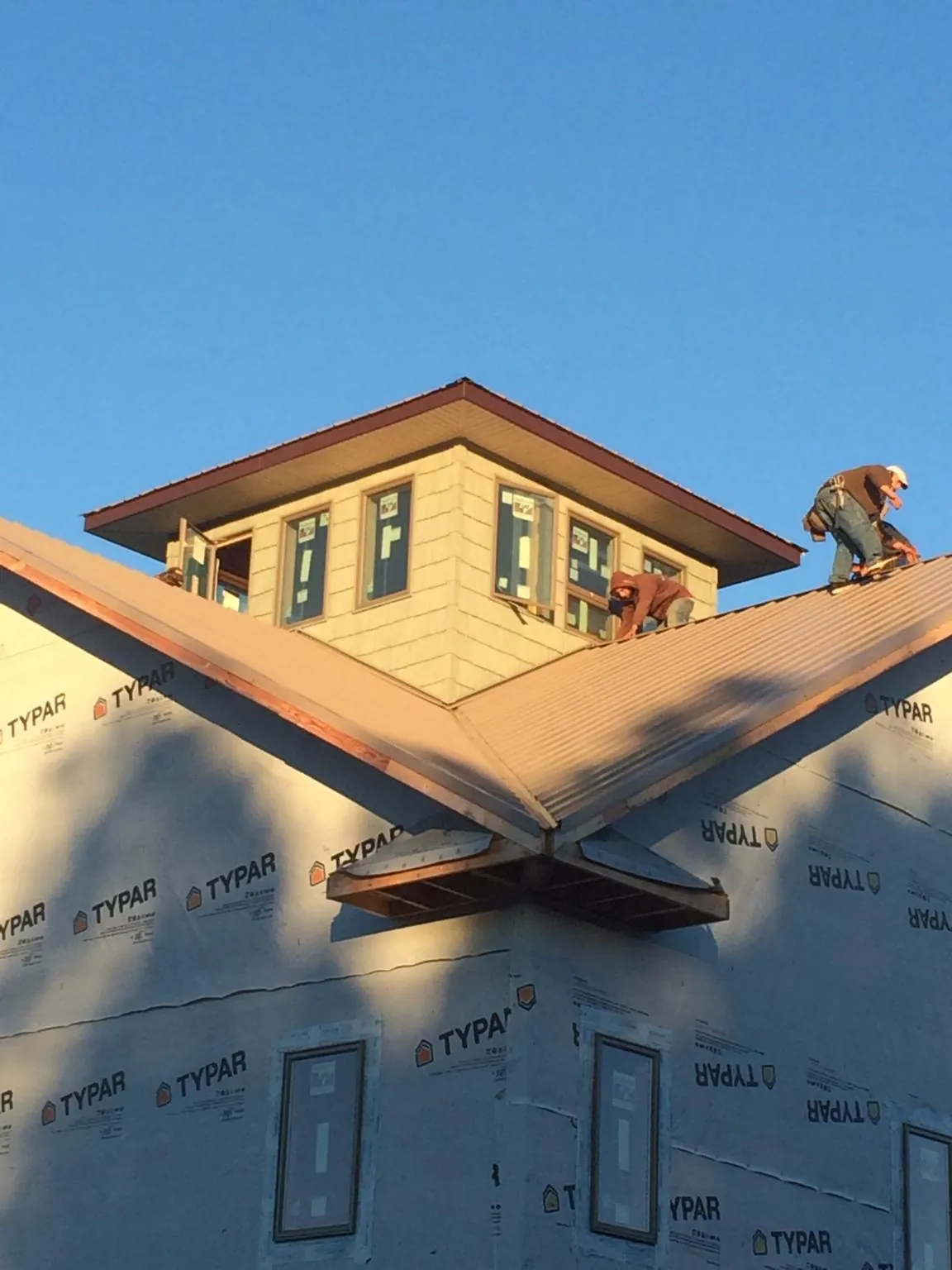 Roofers working around a rooftop cupola on a new metal roof at sunset — Roof Waterproofing in Bogart by Roofing Brothers